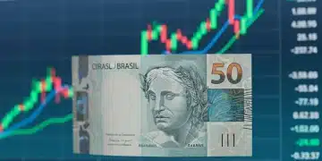 Nota de real com gráficos financeiros ao fundo, simbolizando investimentos e finanças.